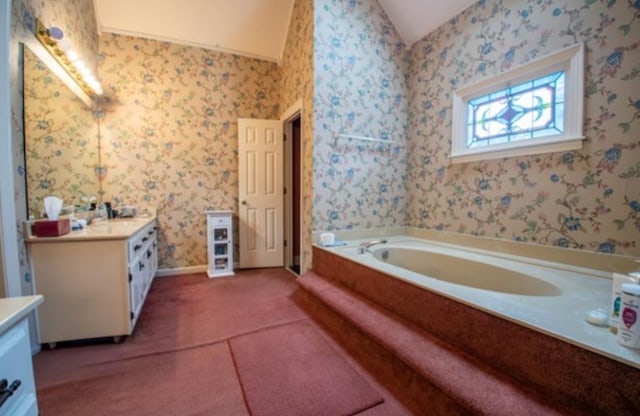 bathroom with vanity, vaulted ceiling, and a washtub