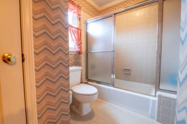 bathroom featuring toilet, combined bath / shower with glass door, crown molding, and tile patterned floors