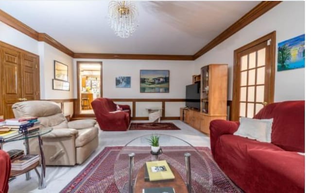 living room featuring light colored carpet, crown molding, and a chandelier