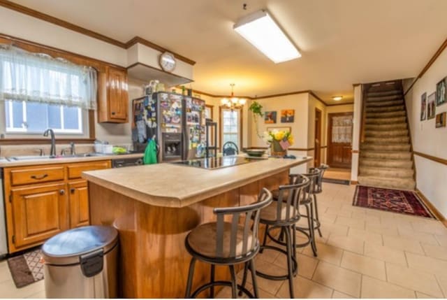 kitchen featuring stainless steel fridge, a kitchen island with sink, a wealth of natural light, a breakfast bar, and sink