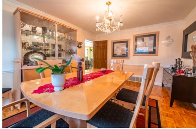 dining room with light parquet flooring, ornamental molding, and an inviting chandelier