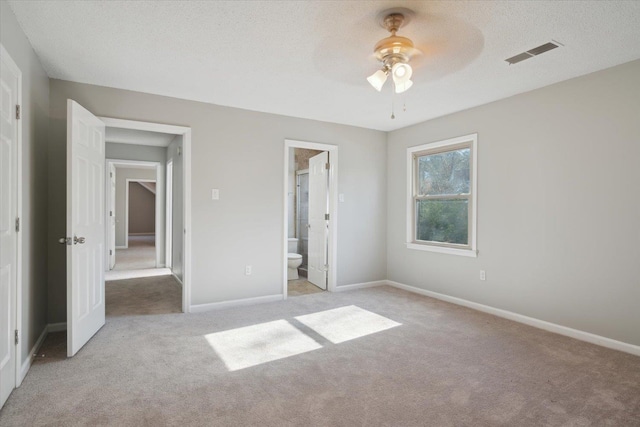 unfurnished bedroom featuring light colored carpet, visible vents, a textured ceiling, and baseboards