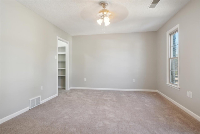 empty room with visible vents, a ceiling fan, light carpet, a textured ceiling, and baseboards