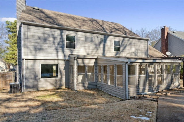 back of house featuring a chimney, a sunroom, and central air condition unit