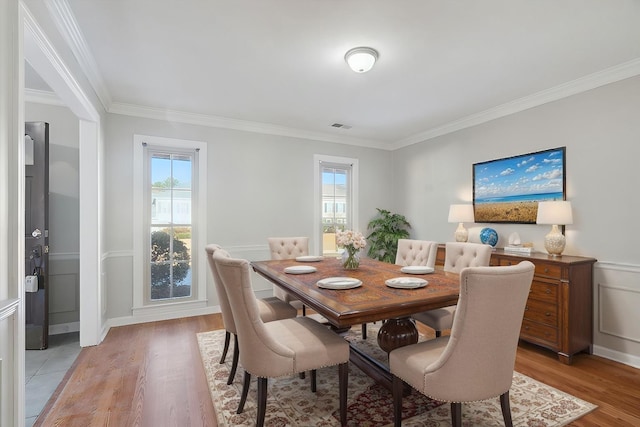 dining space featuring light wood-type flooring, visible vents, and crown molding