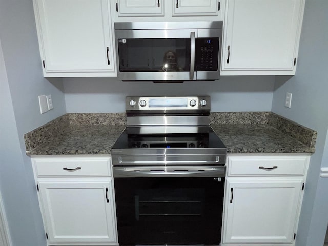 kitchen with white cabinetry, stainless steel appliances, and dark stone countertops