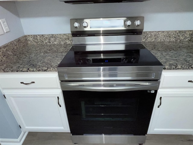 kitchen with white cabinets, stainless steel range with electric cooktop, and stone counters