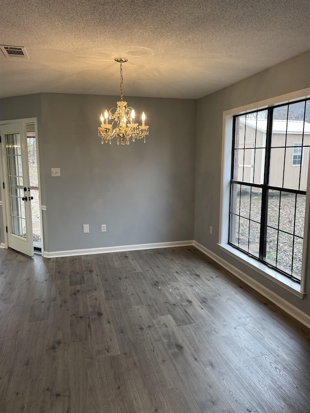 spare room with a healthy amount of sunlight, dark hardwood / wood-style floors, and an inviting chandelier