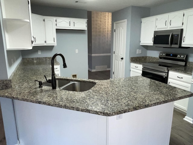 kitchen with appliances with stainless steel finishes, sink, white cabinetry, and dark stone counters