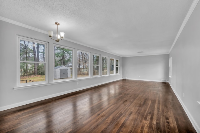 unfurnished living room featuring dark wood-type flooring, a textured ceiling, ornamental molding, and an inviting chandelier