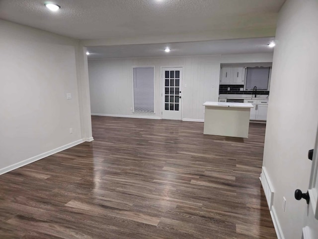 unfurnished living room featuring dark hardwood / wood-style flooring, sink, and a textured ceiling