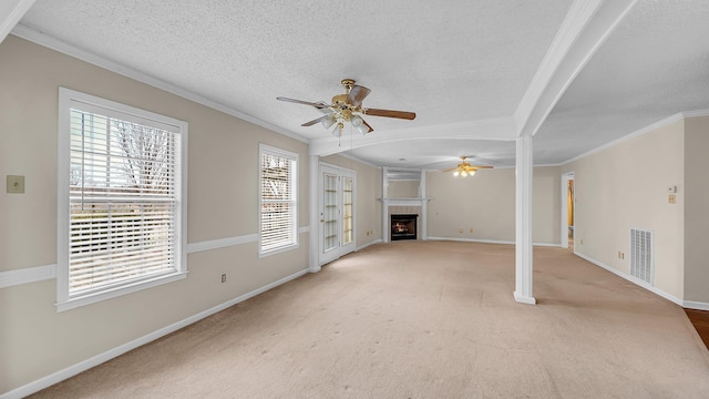 unfurnished living room with a textured ceiling, ceiling fan, crown molding, and light carpet