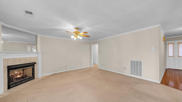 unfurnished living room featuring ceiling fan, a textured ceiling, a tile fireplace, and crown molding