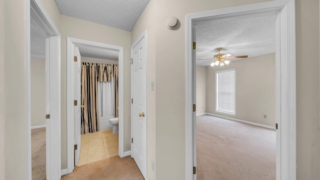 corridor featuring light colored carpet and a textured ceiling