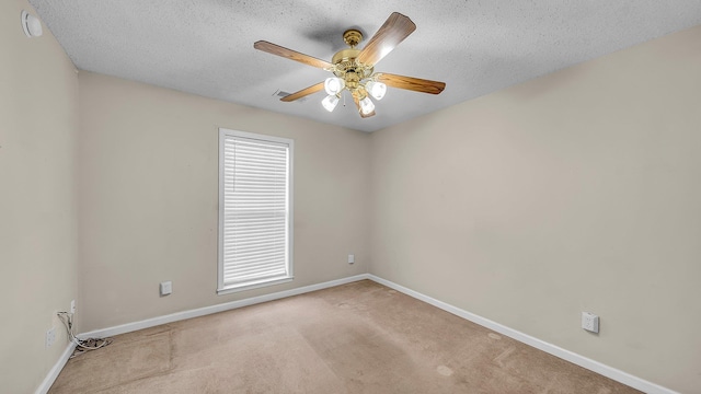 spare room with ceiling fan, a textured ceiling, and light carpet