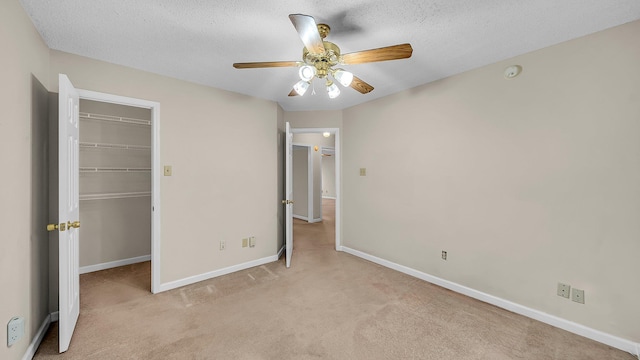 unfurnished bedroom with ceiling fan, light colored carpet, a closet, and a textured ceiling