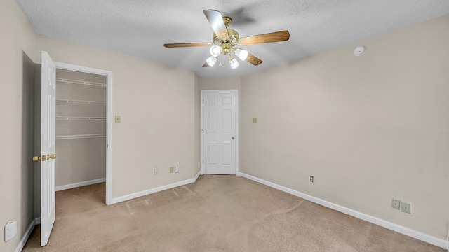 unfurnished bedroom with ceiling fan, a textured ceiling, and light carpet