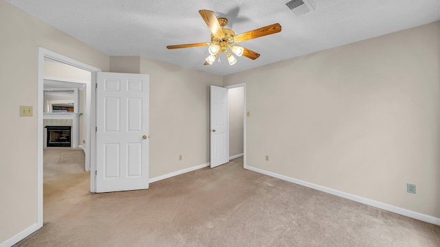 unfurnished bedroom with light carpet, ceiling fan, a closet, and a textured ceiling