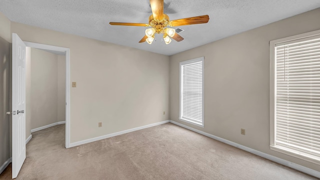 empty room featuring light carpet, ceiling fan, and a textured ceiling