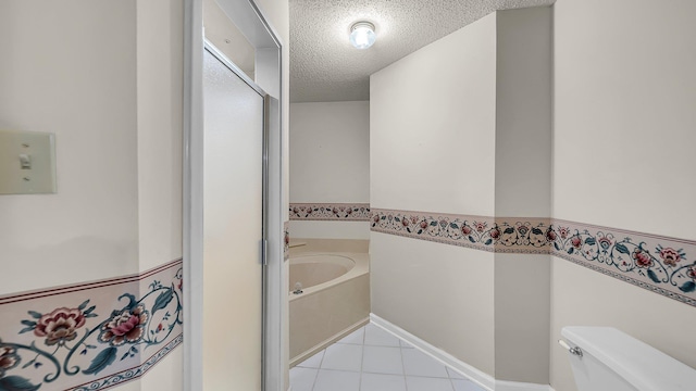 bathroom with toilet, tile patterned flooring, a textured ceiling, and a bath