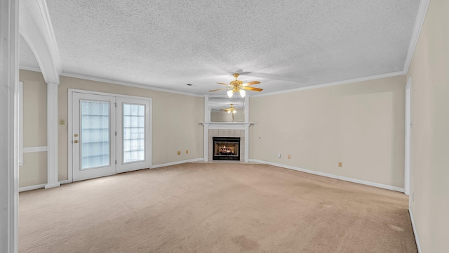 unfurnished living room featuring a textured ceiling, light carpet, ornamental molding, ceiling fan, and a tiled fireplace