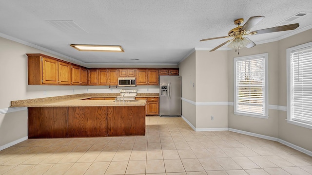 kitchen featuring kitchen peninsula, ornamental molding, stainless steel appliances, and a textured ceiling