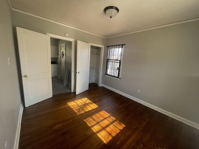 unfurnished bedroom featuring a closet, ornamental molding, and dark hardwood / wood-style floors