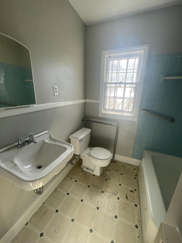 bathroom with toilet, a bath, and sink