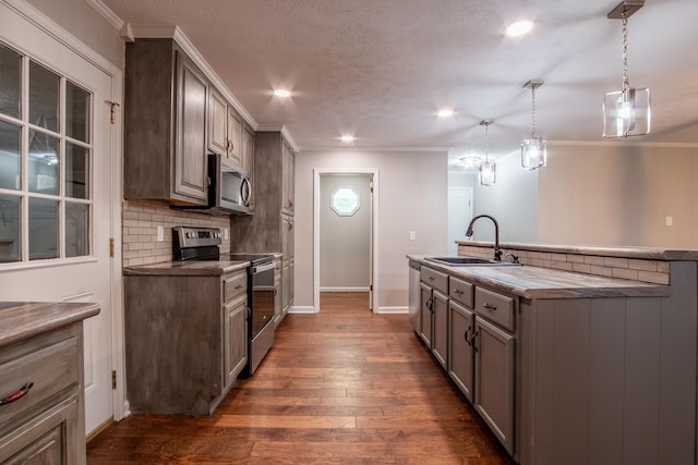 kitchen with appliances with stainless steel finishes, tasteful backsplash, dark wood-type flooring, pendant lighting, and sink