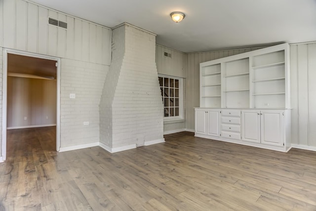 unfurnished living room featuring hardwood / wood-style flooring and wood walls