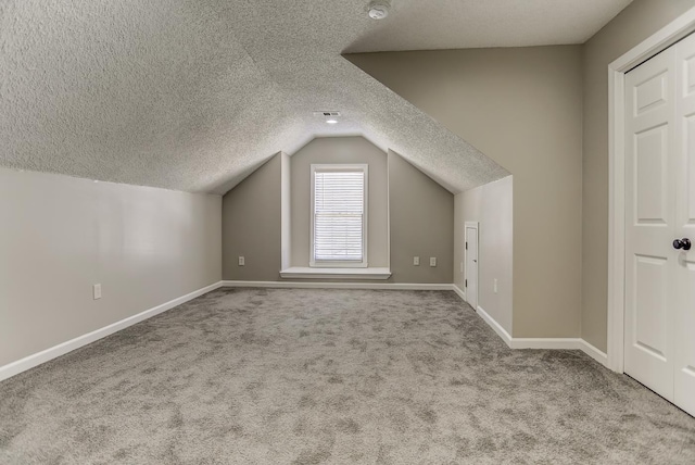 additional living space featuring light colored carpet, a textured ceiling, and lofted ceiling