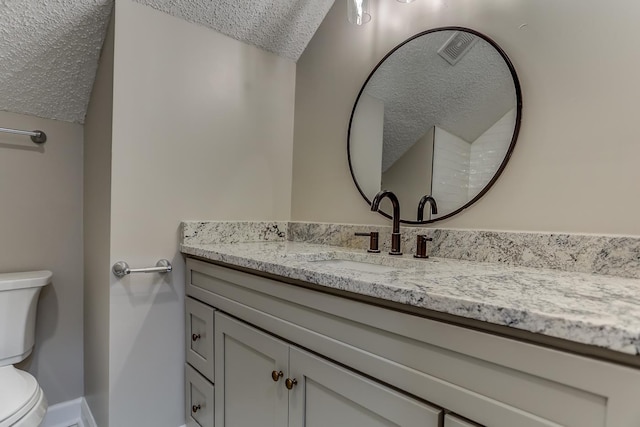 bathroom featuring a textured ceiling, toilet, and vanity