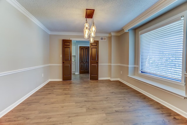 unfurnished dining area with a textured ceiling, ornamental molding, and hardwood / wood-style floors