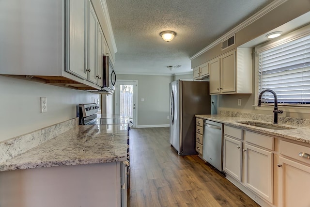 kitchen featuring light stone countertops, a textured ceiling, stainless steel appliances, sink, and ornamental molding