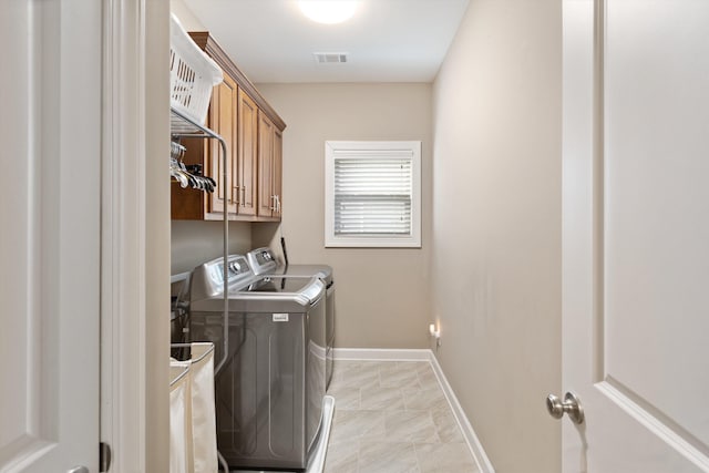 clothes washing area with cabinets and washing machine and dryer