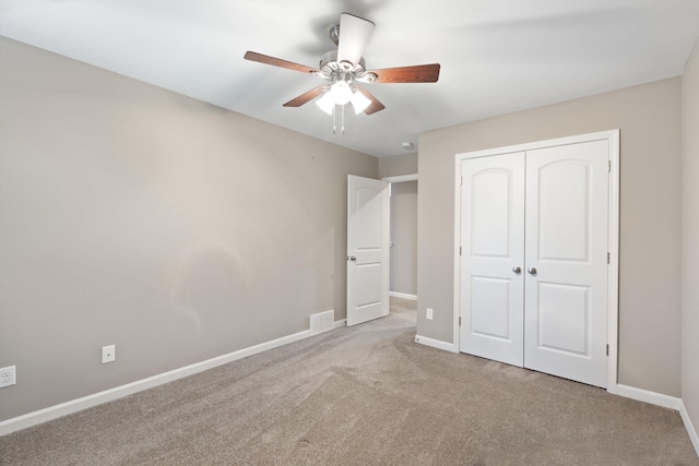 unfurnished bedroom featuring ceiling fan, a closet, and light carpet