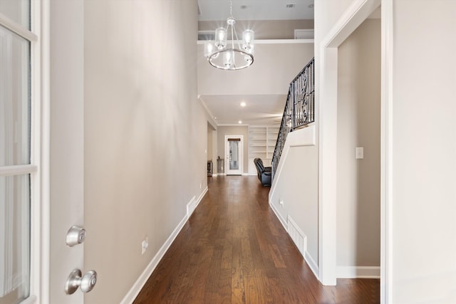 hallway with dark hardwood / wood-style flooring, ornamental molding, and a chandelier