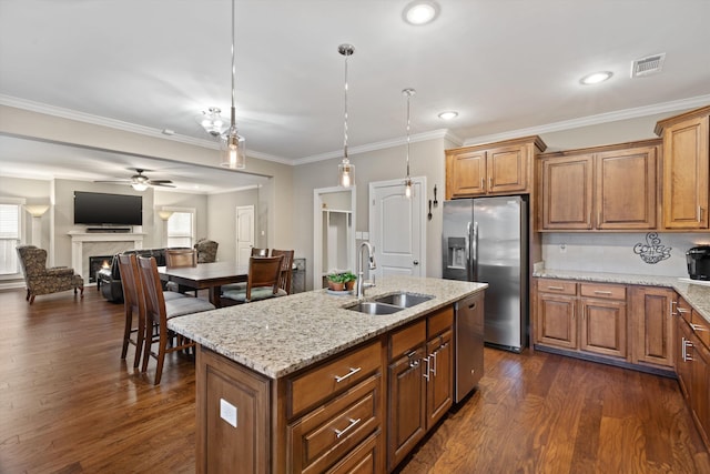 kitchen with stainless steel appliances, sink, hanging light fixtures, ornamental molding, and a center island with sink