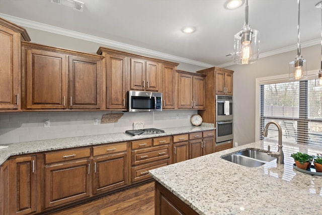 kitchen with decorative light fixtures, sink, crown molding, and stainless steel appliances