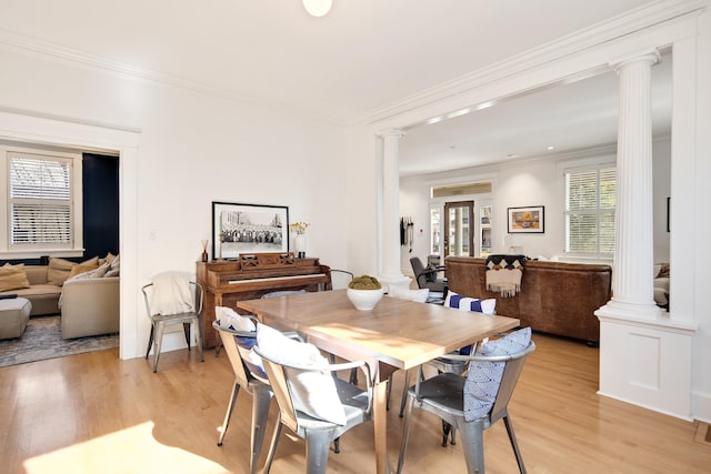 dining area with light hardwood / wood-style flooring, ornamental molding, and decorative columns