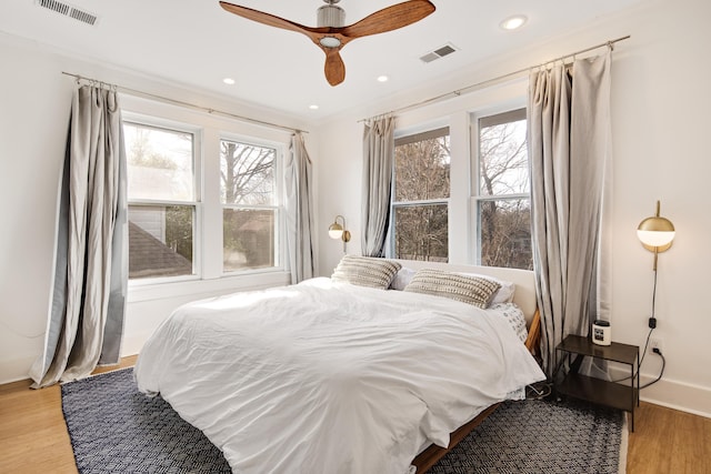 bedroom with light wood-type flooring, ceiling fan, and crown molding