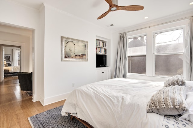 bedroom with ceiling fan, ornamental molding, and light hardwood / wood-style floors