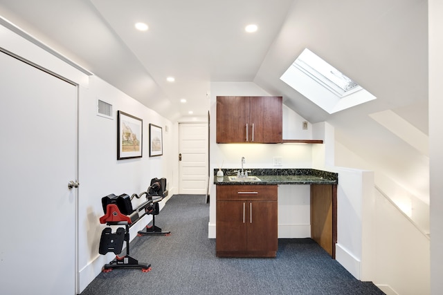 kitchen featuring sink, dark carpet, and lofted ceiling with skylight