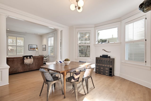 dining area with light wood-type flooring, ornate columns, a chandelier, and crown molding