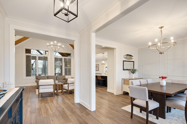 dining space with vaulted ceiling, light hardwood / wood-style flooring, crown molding, and an inviting chandelier