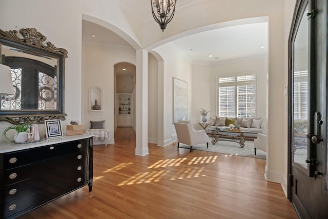 foyer entrance with ornamental molding, a notable chandelier, and light wood-type flooring