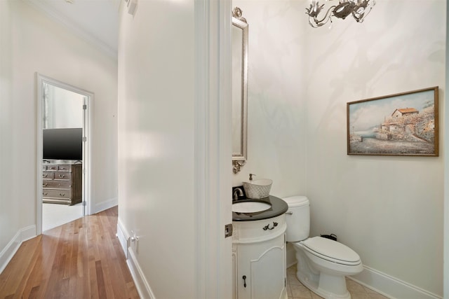 bathroom with toilet, ornamental molding, hardwood / wood-style floors, and vanity