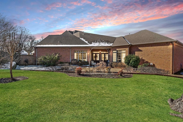 back house at dusk with a patio area and a yard