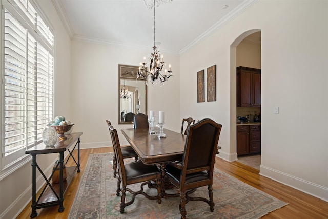 dining space featuring light wood-type flooring, a wealth of natural light, and ornamental molding