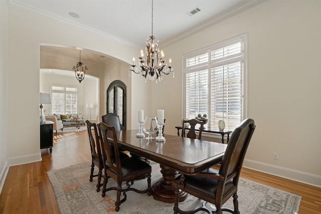 dining space featuring an inviting chandelier, crown molding, and light hardwood / wood-style flooring